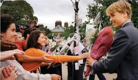  ??  ?? Forcing a smile: William receives flowers at Kensington Palace as he inspects tributes the day before Diana’s funeral