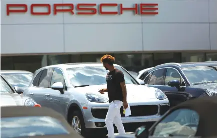 ??  ?? A MAN WALKS PAST VARIOUS NEW Porsche models on a dealer’s lot in Silver Spring, Maryland, US, June 1.