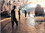  ??  ?? Thai soldiers, right, try to connect water pipes to divert water from the mountains above the cave, left, where their comrades are working to jelp rescue the 12 boys and their coach