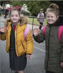  ??  ?? Ellie Rose O’Brien and Daisy Devlin wave goodbye to their old school as they walk to the new building on Monday morning.