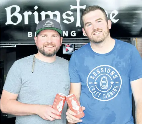  ?? KRIS DUBE/SPECIAL TO POSTMEDIA NEWS ?? Matty MacGregor from Crave Gastropub and Zack Gagnon from the Brimstone Brewing Company with new cans of Sinister Minister, a popular beer brewed at the popular spot in downtown Ridgeway.