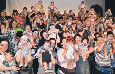  ?? Korea Times file ?? Parents hold their babies during an event to promote breast-feeding at Haeundae Grand Hotel in Busan, Aug. 31. In a survey by The Korea Times, economists and analysts have picked Korea’s demographi­c change and low birthrate as the country’s biggest...