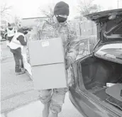  ?? TONY DEJAK/AP ?? Staff Sgt. Mike Schuster loads two boxes of produce into a car at a food bank distributi­on event by the Greater Cleveland Food Bank on Jan. 7 in Ohio.