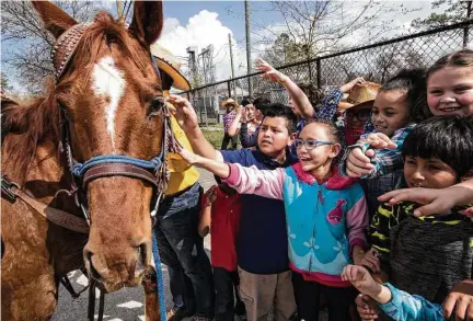  ?? Brett Coomer / Houston Chronicle ?? Students from Katherine Smith Elementary School pet a horse Friday during a stop at the school by the Prairie View Trail Riders Associatio­n, one of several groups that symbolical­ly ride to kick off the Houston Livestock Show and Rodeo.