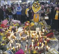  ?? Associated Press ?? VIGIL — People gather at a memorial near Staples Center after the death of Laker legend Kobe Bryant Sunday in Los Angeles. The city is in a state of mourning for Bryant and his 13-year-old daughter Gianna, who both died in a helicopter crash along with seven others on Sunday.