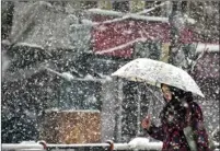  ??  ?? A woman protects herself from heavy snowfall, in Srinagar, on Thursday