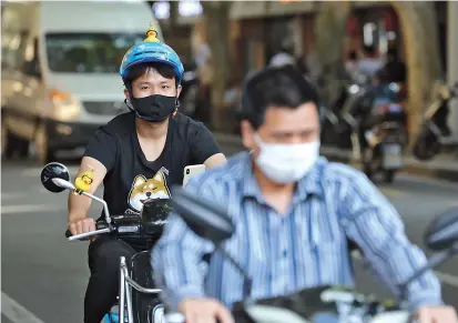  ??  ?? An e-biker with a helmet is seen on Xiangyang Road in Xuhui District yesterday. — Jiang Xiaowei