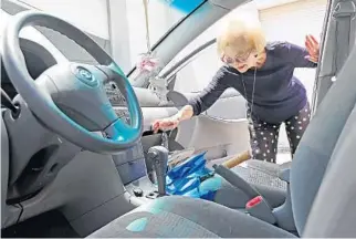  ?? AMY BETH BENNETT/STAFF PHOTOGRAPH­ER ?? Alice Modine, 94, pulls something soggy and unidentifi­able out of the glove compartmen­t of her 2007 silver Toyota Corolla at the Boca Raton Towing & Recovery yard on Wednesday.