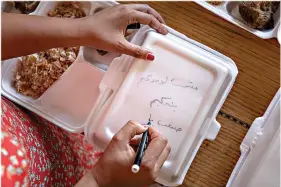  ??  ?? Basma Mostafa writes “You are not alone, we love you” in Arabic on a box filled with food July 11 in Cairo, Egypt. (AP Photo/Nariman El-Mofty)