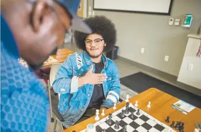  ?? Photos by Shaban Athuman, The Denver Post ?? Elijah Beauford, right, talks to Phillip Douglas, founder and executive director of Make A Chess Move, a nonprofit club in Denver that teaches young people how to play chess and how to apply the strategy in the game to decision-making in life. “That’s our motto — make your next move your best move,” Douglas says.