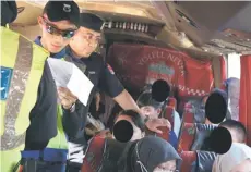  ?? ?? Security personnel screening passengers on a bus during the operation in Beluran.