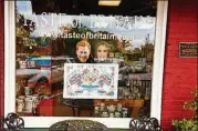  ??  ?? Harry and Meghan masks above a royal wedding tea towel peer out at passersby from the window of Taste of Britain in historic Norcross.