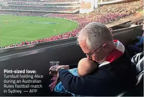  ??  ?? Pint-sized love: Turnbull holding Alice during an Australian Rules football match in Sydney. — AFP