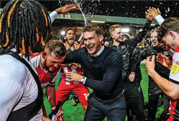  ?? Phil Mingo/PPAUK ?? >
Exeter City manager Matt Taylor is sprayed with champagne as the Grecians celebrate opromotion to Sky Bet League One on Tuesday night