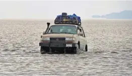  ??  ?? Arriba: operadores de turismo cruzando el salar de Uyuni, sorprenden­temente con agua. Abajo: en la balsa que ayuda a sortear parte del lago Titicaca.