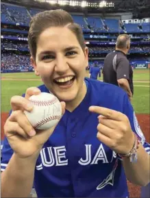  ?? NEW YORK TIMES FILE PHOTO ?? Michelle Cherny, the treasurer for Pride Toronto, holds up a baseball that was autographe­d by Kevin Pillar after she threw out the ceremonial first pitch last Thursday.