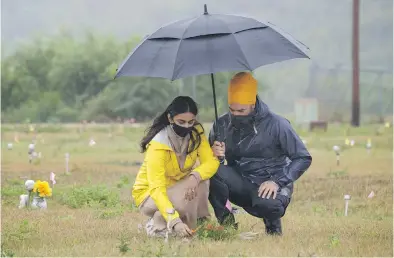  ?? PAUL CHIASSON, THE CANADIAN PRESS ?? NDP Leader Jagmeet Singh and his wife Gurkiran Kaur Sidhu place flowers on a grave where 751 bodies were buried on the grounds of the Marieval Indian Residentia­l School on Cowessess First Nation, Sask.