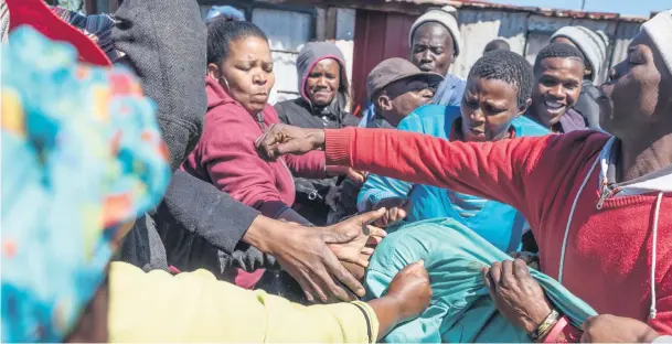  ?? Pictures: Yeshiel Panchia ?? MOB CLOSES IN. Silvertown Extension 4 residents attack a man who allegedly murdered his wife in the township this week. The man was accosted and beaten by the community and later hanged himself while being kept prisoner in his house.