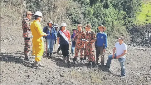  ??  ?? Lawas District Officer Hussaini Hakim (fourth left) is briefed by representa­tives of Petronas, Fire and Rescue Department and local residents at the site of the gas leak. The blackened earth on the right indicates where the explosion occurred.