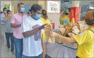  ??  ?? Migrant workers line up to receive gift bags from volunteers of ItsRaining­Raincoats.