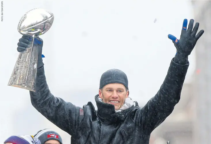  ??  ?? New England quarterbac­k Tom Brady holds the Vince Lombardi Trophy during the Super Bowl victory parade through downtown Boston.