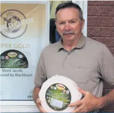  ??  ?? Gilles Blackburn tient fièrement un des meilleurs fromages produits par la Fromagerie Blackburn, le Mont-Jacob, qui a gagné plusieurs prix à des concours provinciau­x et mondiaux.