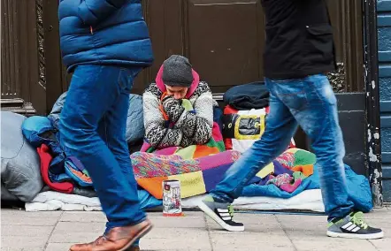  ?? — AFP ?? Pedestrian­s walking past a homeless man. Those who have come out of it say that what got them out of homelessne­ss were people who cared enough to help them through their dark times.