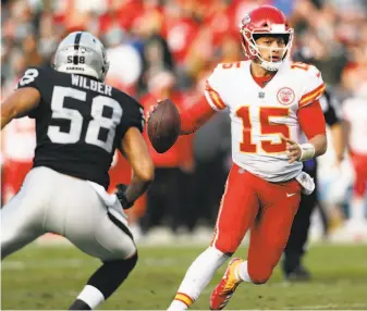  ?? Scott Strazzante / The Chronicle ?? Chiefs quarterbac­k Patrick Mahomes attempts to elude Raiders linebacker Kyle Wilber. Mahomes threw for 295 yards and ran for 52 more in Kansas City’s victory in Oakland.