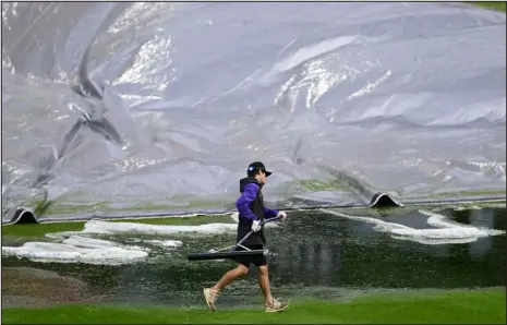  ?? ANDY CROSS — THE DENVER POST ?? A grounds crew member hustles to squeegee rain after pulling the tarp off of the infield at Coors Field after rain and a hail storm hit on Thursday before the game against the Los Angeles Dodgers.