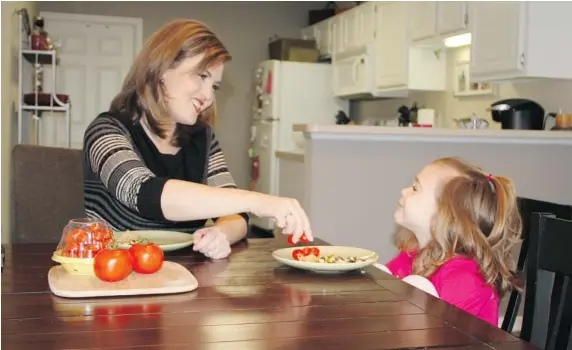  ?? ROBERT LEITCH/The Associated Press ?? Shannon McCormick serves a tomato to her daughter Sophie Chapman, 4, at their home in Gahanna, Ohio. Although not fond of tomatoes, McCormick keeps that fact from her daughter.