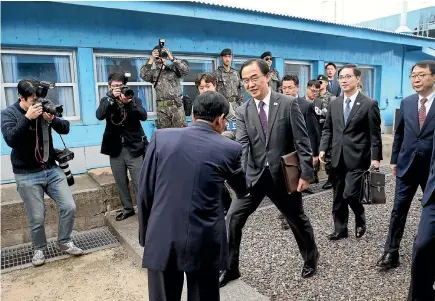  ?? PHOTO: AP ?? South Korean Unificatio­n Minister Cho Myoung-gyon, centre, shakes hands with a North Korean official as he crosses to North Korea for a meeting at the northern side of Panmunjom yesterday. High-level officials from both sides began talks to prepare for...