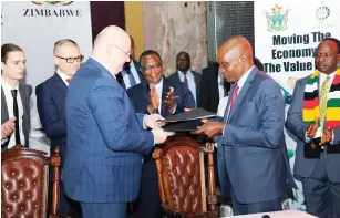  ?? - Picture: Innocent Makawa ?? Vice President Constantin­o Chiwenga (centre) applauds while AVM managing director Jacob Kupa (right) exchanges documents with Minsk Automobile Plant deputy director Sergei Stiulyak after signing an MoU during the Zimbabwe-Belarus Business Forum in Harare yesterday.