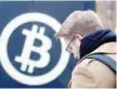  ?? — AFP ?? A man walks past a bitcoin logo at an exchange house in Berlin.