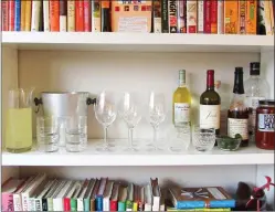  ?? LAURA AGRA/KATIE WORKMAN VIA AP ?? Above: This November 2015 photo provided by Katie Workman shows a temporary bar for a party being set up in a bookcase in New York. Making the most of different areas of your home is very helpful when you have a big group over. Below: This photo shows napkins, forks and plates on a table in New York. Setting up as much as you can for a party the night before is key. Whatever you can take out and leave out — dishes, napkins, glasses, platters — means less frantic last minute activity the day of.