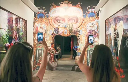  ?? — Photos: AFP ?? Visitors pose for a picture next to an artwork entitled The King Of Pop (centre) by American artist Mark Ryden at London’s National Portrait Gallery.