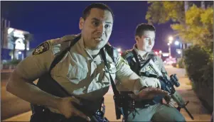  ?? AP PHOTO ?? Police officers advise people to take cover near the scene of a shooting near the Mandalay Bay resort and casino on the Las Vegas Strip.