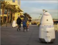  ?? THE ASSOCIATED PRESS ?? Knightscop­e K5 security robots, at right, and background left, patrol alongside a pier April 19 in San Diego. The robots can identify a vehicle parked in a certain location for too long or sense intruders at odd hours. The company expects to have...
