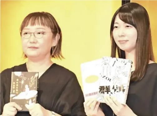  ?? The Yomiuri Shimbun ?? Naoki Prize-winner Misumi Kubo, left, and Akutagawa Prize-winner Junko Takase hold up their winning works in Tokyo on July 20.