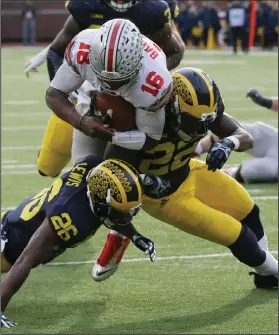  ?? AP PHOTO ?? Ohio State quarterbac­k J.T. Barrett, top, leaps over Michigan cornerback Jourdan Lewis, left, and safety Jarrod Wilson for a touchdown.