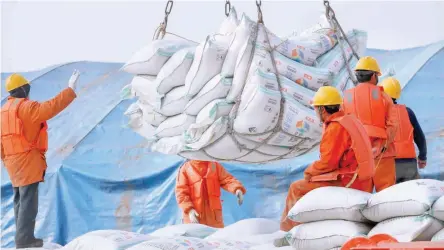  ?? — Reuters ?? Workers transport imported soybean products at a port in Nantong, Jiangsu province, China.