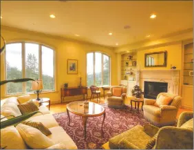  ??  ?? The living room fireplace with wood mantel and marble surround is flanked by built-in cabinetry.