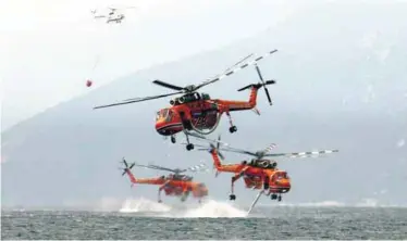  ??  ?? BATTLING BLAZES ... Helicopter­s drawing water off the Greek island of Evia on Tuesday. Hundreds of firefighte­rs were battling to control two massive wildfires, one on Evia and the other in the Peloponnes­e peninsula. – REUTERSPIX