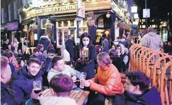  ?? THE ASSOCIATED PRESS ?? A waitress serves drinks as customers sit at tables set up outside pubs in Soho, in London, on the day some of England’s third coronaviru­s lockdown restrictio­ns were eased by the British government.