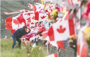  ?? JEFF BASSETT/THE CANADIAN PRESS ?? Jennifer Mcelory of Kamloops places a memorial on the Kamloops Airport fence Thursday. Snowbirds member Capt. Jenn Casey died when the Snowbirds jet she was in crashed Sunday.