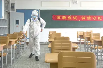  ?? — AFP photos ?? A staff member wearing protective clothing spraying disinfecta­nt at an examinaton room ahead of the National College Entrance Examinatio­n (NCEE), known as Gaokao, in Wuhan in China’s central Hubei province.