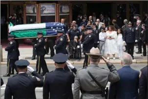  ?? The Associated Press ?? FALLEN HERO: Police officers salute as slain New York City Police officer Miosotis Familia's mother Adriana Valoy, center in wheel chair, son Peter, third from right, and daughters Genesis and Delilah watch as her casket is carried from the World...