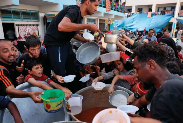  ?? ?? Palaestine­nsiske børn får mad på en FN-skole i Rafah i det sydlige Gaza. Mange hundredtus­inder er stuvet sammen her, fordi kampene mellem Israel og Hamas er rykket til det centrale Gaza. Foto: AFP