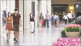  ?? Ryan Michalesko / Associated Press ?? Shoppers walk through NorthPark Center mall Friday in Dallas, Texas. Gov. Greg Abbott's executive order requiring Texans to stay at home expired on the day before, allowing businesses to reopen under certain conditions. Stores, restaurant­s and movie theaters may open as long as they maintain 25 percent occupancy and follow social distancing. Under those guidelines, malls can also open but food courts, play areas and interactiv­e displays or settings must remain closed.