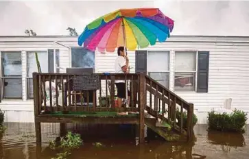  ?? EPA PIC ?? Erick Martinez grilling chicken on the porch of his home as floodwater­s from Hurricane Florence rise in the Magnolia Mobile Home Park north of Lumberton, North Carolina, on Sunday.