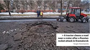  ?? Yevgen Honcharenk­o ?? A tractor cleans a road near a crater after a Russian rocket attack in Kramatorsk